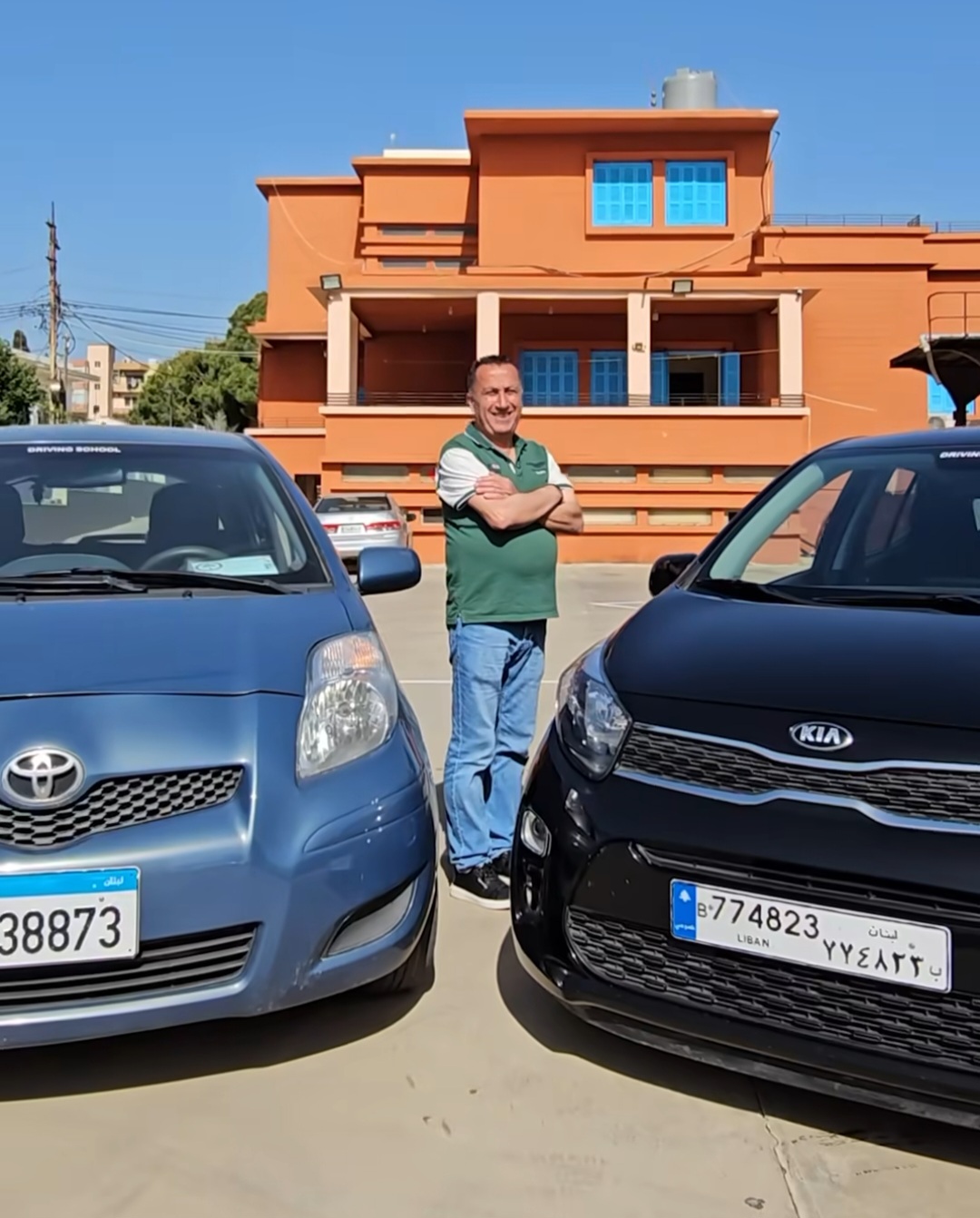Michel Hannouch standing between two driving-school cars